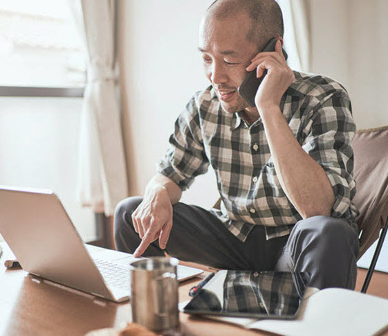 Man talking on the phone while using a laptop